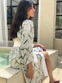 a woman is sitting on the edge of a pool in a white robe