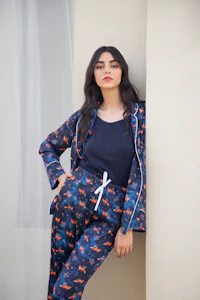 a woman in a blue pyjama set leaning against a wall