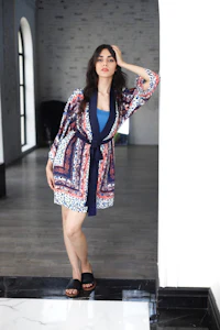 a woman in a blue and white patterned robe posing in a hallway